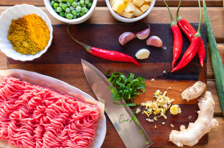 Ground beef being prepped with other spices and aromatics
